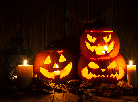 Halloween Jack-o-Lantern Pumpkins on rustic wooden background