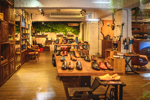 Display of a high quality luxury footwear boutique for stylish men. Designer shoes made by professional shoemakers for fashion lovers and executive businessmen. Photographed through window.