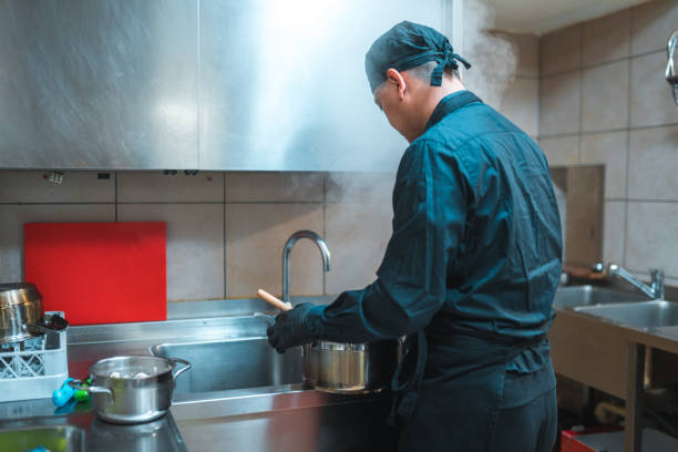 Healthcre worker washing the dishes and chatting to the lady she is helping