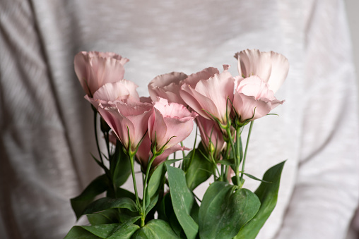 Bouquet of light pink flowers with fresh green leaves on a white background