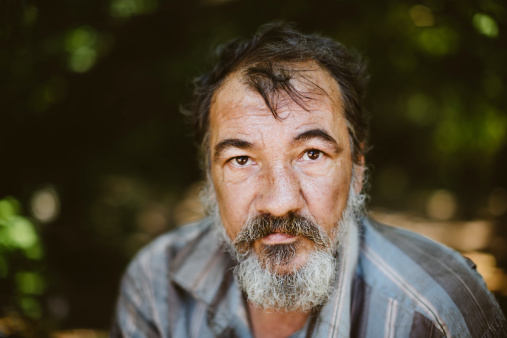 real homeless man on the foliage background, selective focus on eye