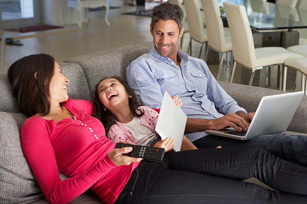família feliz no sofá com laptop e tablet - family sofa night indoors - fotografias e filmes do acervo