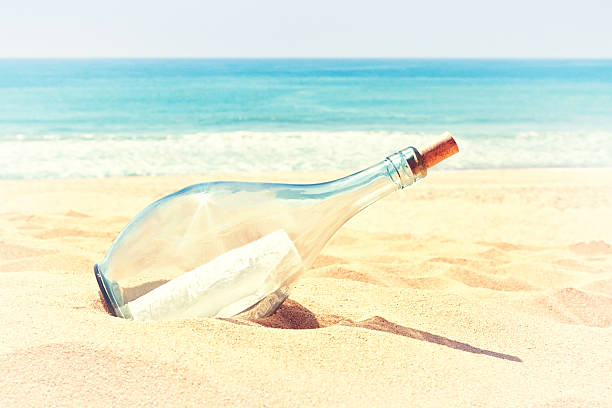 istock Bottle with a letter of distress in sand on beach. 174181413