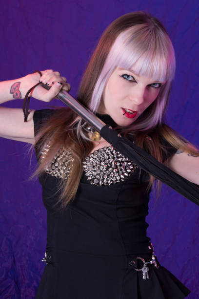 istock Dominatrix in black holding flogger under chin. 174181592