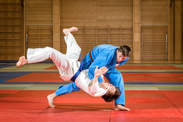 An action shot of young male judoka fighters in a dojo young judokas fighting in dojo  judo stock pictures, royalty-free photos & images