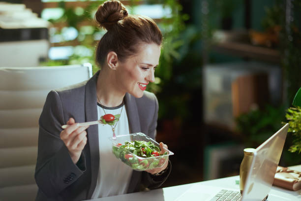 istock smiling female worker in green office eating salad 1741840032