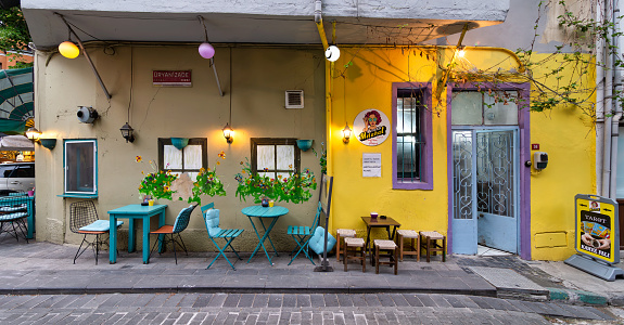 Istanbul, Turkey - May 9, 2023: Alley in front of a yellow and purple street cafe with outdoor tables and chairs, located in Kuzguncuk neighborhood, Uskudar district on the Asian side of Istanbul