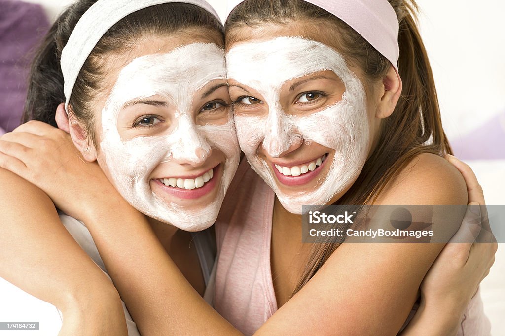 Blissful girls applying mask hugging each other Blissful girls applying white facial mask hugging each other Adult Stock Photo
