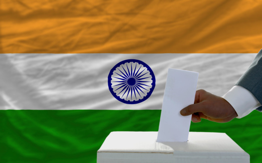man putting ballot in a box during elections  in front of national flag of india