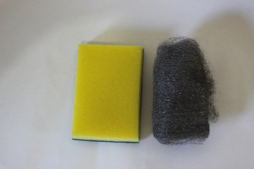 Yellow sponge for cleaning cutlery, glasses, and plates, and a steel wool for cleaning pans and heavier use.