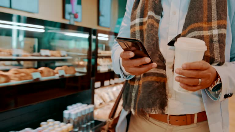 Phone, coffee and hands of person typing in cafe on social media, internet search and walking. Smartphone, tea and closeup of professional in restaurant, scroll on mobile app and drink espresso