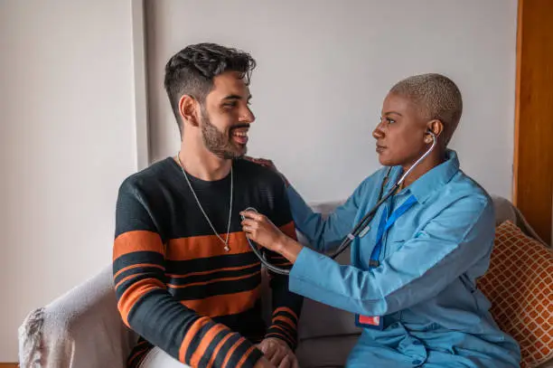 Doctor examines patient with stethoscope at home