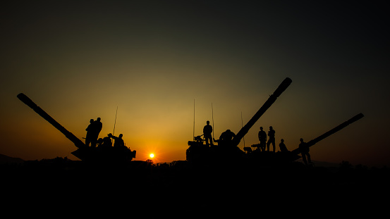silhouette group of special forces sodiers standing and sit on tank gun truck with over the sunset background, special warfare training operations teams,
