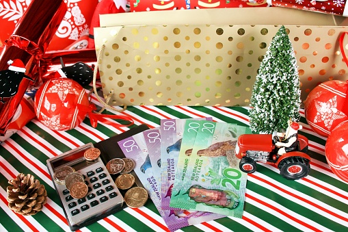 Christmas decorations and wrapping paper with NZD New Zealand Dollars and a calculator for a cost of Christmas or a saving for Christmas concept.