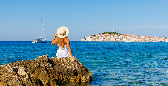 Young female tourist sitting on rock and looking at city in Croatia- Dalmatia- travel, tour tourism,vacation