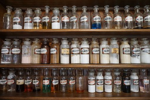 Display of shelves with old fashioned medicine bottles with powders and liquids at chemist