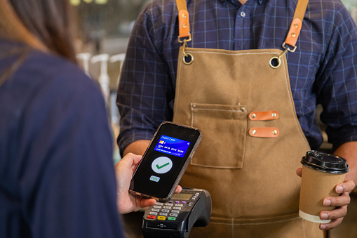 Close up baristas or cashier worker hold payment machine accept credit card cashless transaction from customer, Smart employee hands payment scanners to customers in cafe shop, pay for morning coffee.