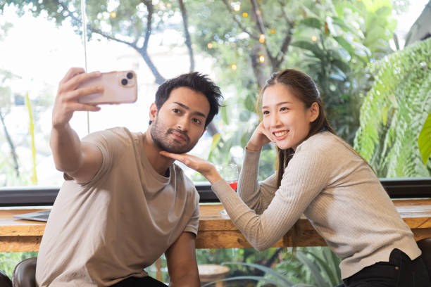 Happy couple enjoy taking selfie together in coffee shop. Beautiful Asian woman and Indian man meet at cafe to date together on anniversary. Lifestyle concept in love having date sit at restaurant Happy couple enjoy taking selfie together in coffee shop. Beautiful Asian woman and Indian man meet at cafe to date together on anniversary. Lifestyle concept in love having date sit at restaurant asian attracted stock pictures, royalty-free photos & images