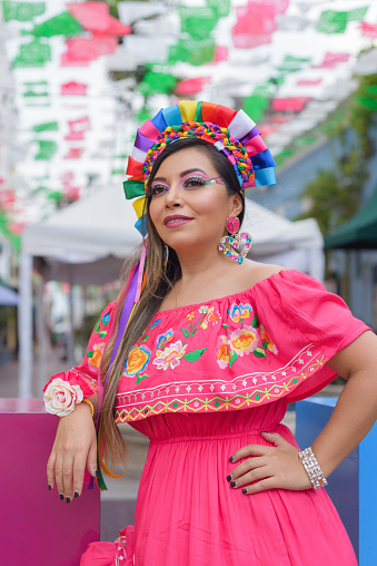 Street portrait of Mexican woman wearing traditional dress with multicolored embroidery. Hispanic woman celebrating independence day.