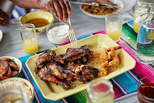 Black family enjoying Jamaican food for summertime lunch on veranda.