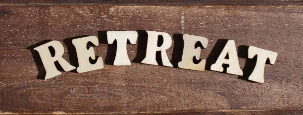 nature wooden letters in the sun on a sunny day. create the word RETREAT from wooden letter alphabet. background is made from naturally wood.