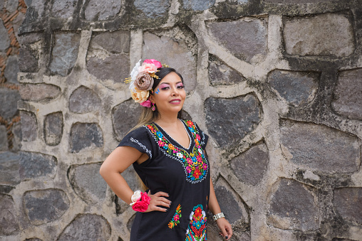 Street portrait of Mexican woman wearing traditional dress with multicolored embroidery. Hispanic woman celebrating independence day.