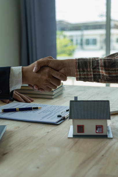 a sales representative shakes hands with a customer and offers a home purchase contract to purchase the current home and a proposed lease for the homeowner. close-up. - house real estate key residential structure imagens e fotografias de stock