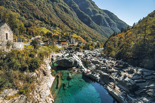 rocks in turquoise river in the verzasca valley in the swiss ticino canton with village Lavertezzo in the background