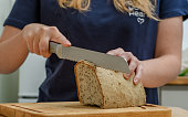 Woman cuts bread with a bread knife, close up