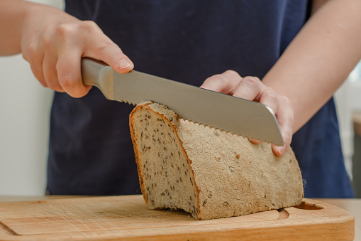 Cutting bread with a kitchen knife in the kitchen closeup