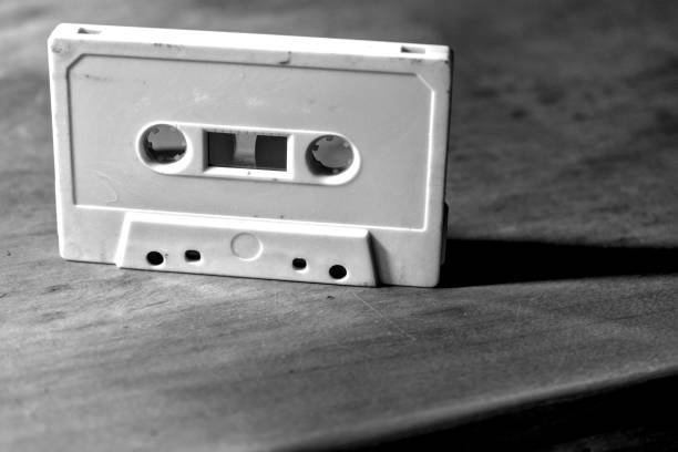 Monochrome old audio cassette on a wooden table.