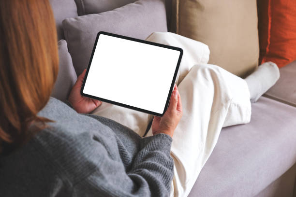 istock Mockup image of a woman holding digital tablet with blank desktop screen while lying on a sofa at home 1742232769