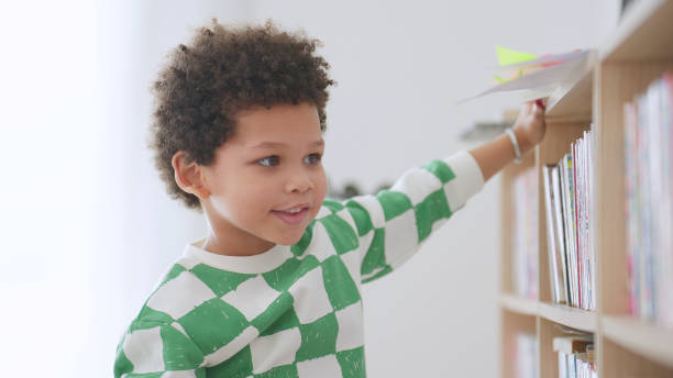 istock Happy African american kindergarten student finding a books for learning in library at school. Child boy in school library. Education and learning concept 1742248745
