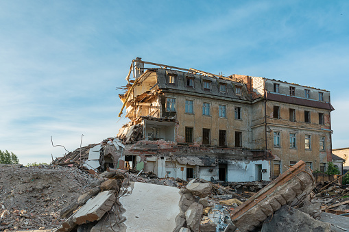 Destroyed residental building. A large destroyed house with broken apartments and a pile of construction debris. Buildings damaged by terrorist attack, war or earthquake.