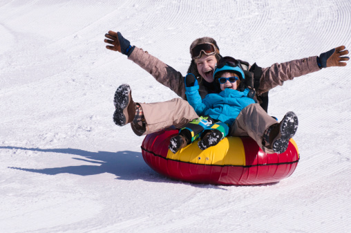Young woman and child tubing down the hill and having fun