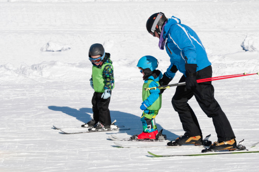 Skiing instructor working with two little boys