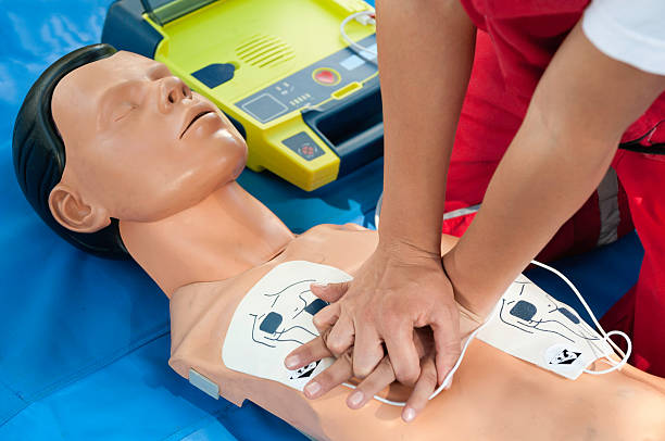 CPR Defibrillator Training CPR training - Chest compressions combined with defibrillator operation performed on a CPR dummy. Focus on hands defibrillator photos stock pictures, royalty-free photos & images