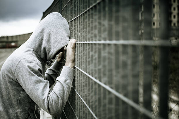 istock Lonely Man with Hood Leaning on a Fence 174225991