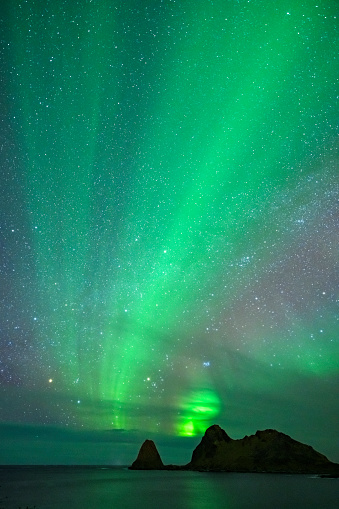 Norhtern Lights or aurora  over Nykvag beach with a starry sky in Northern Norway during a cold winter night.