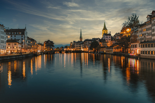 illuminated cityscape of old town zurich at riverside at sunset hour