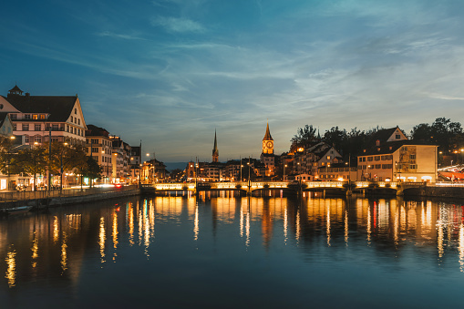 illuminated cityscape of old town zurich at riverside at sunset hour