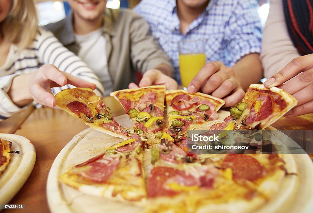 Appetizing pizza Image of teenage friends hands taking slices of pizza Pizza Stock Photo