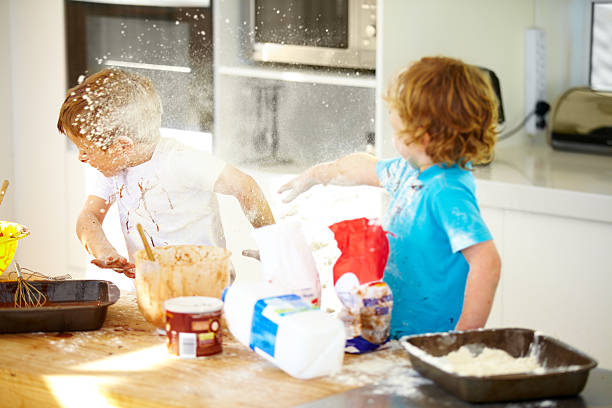 Things are getting out of control in here! Little boys covered in baking ingredients during a messy baking session child behaving badly stock pictures, royalty-free photos & images