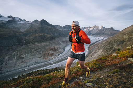 Senior male trail runner bounds along mountain trail