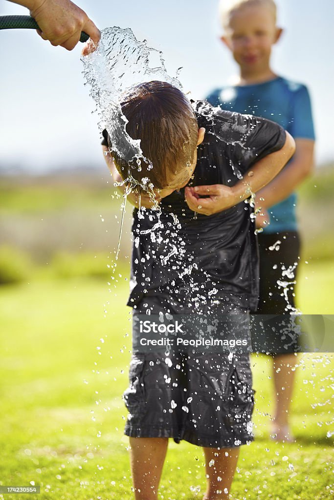 Having summer fun without a pool Little boys getting wet by a hose pipe while outdoors Adult Stock Photo