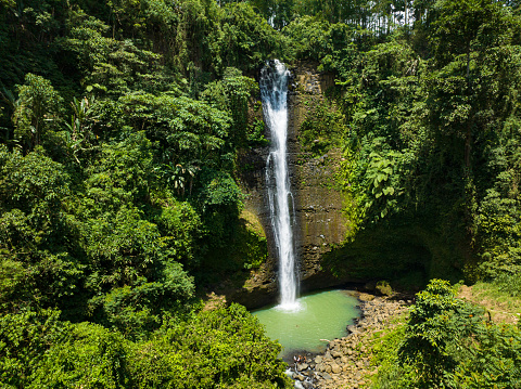 Alalum Falls with green plunge pool surrounded by lush vegetation. Mindanao, Philippines.