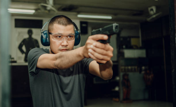 istock A professional man wearing earmuffs and goggles is practicing shooting a 9mm pistol inside a shooting range. 1742320114