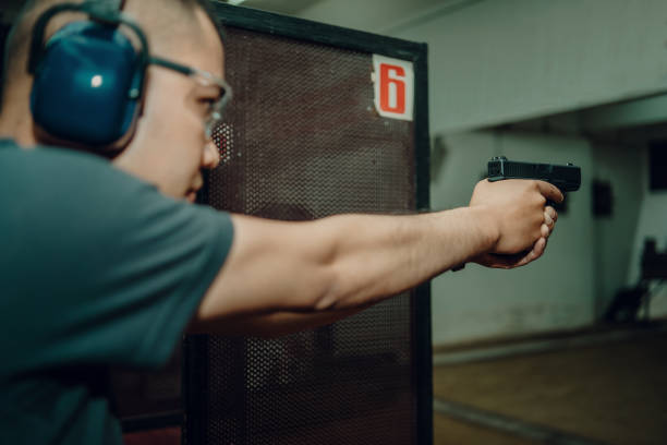 istock A professional man wearing earmuffs and goggles is practicing shooting a 9mm pistol inside a shooting range. 1742320132