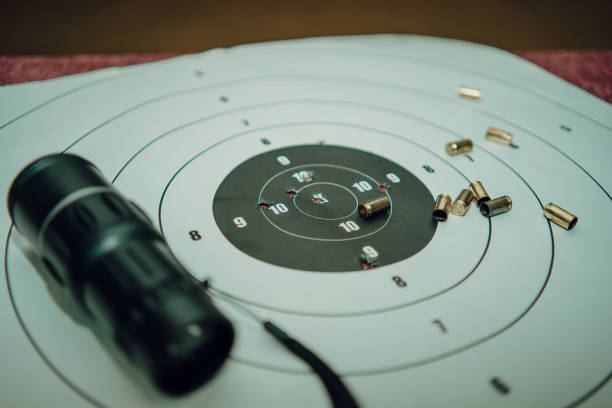 die pistole ruht auf einer zielscheibe mit einem einschussloch. nahaufnahme - bullet hole target target shooting bulls eye stock-fotos und bilder