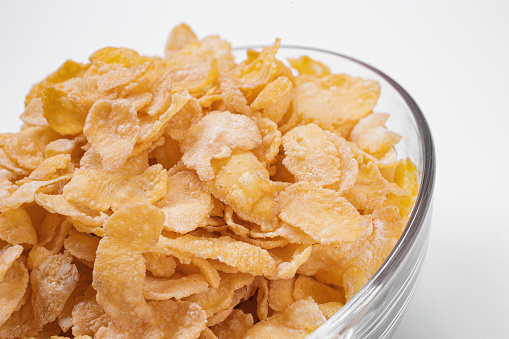 corn flakes inside glass bowl close-up top view on white background